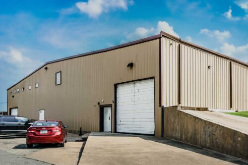 The large Sonance Rehearsal Studios Brown Lane industrial warehouse of rehearsal rooms featuring two white garage doors and two small access doors.